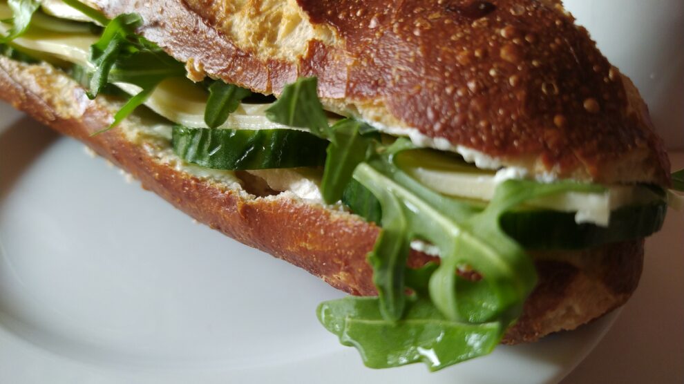 Leckere Laugenstange, belegt mit Käse und Rucola